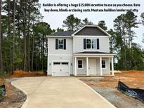 Charming two-story home featuring a light exterior, attached garage, and inviting front porch with stately columns at 187 Regis Ln # 10, Coats, NC 27521