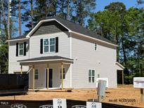 New two-story home featuring light siding, black shutters, and a covered front porch nestled on a wooded lot at 187 Regis Ln # 10, Coats, NC 27521