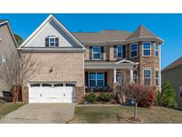 Inviting exterior showcasing a brick facade, two-car garage, manicured lawn, and covered front porch at 1950 Firenza Dr, Apex, NC 27502