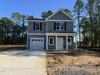 Charming two-story home featuring gray siding, a welcoming front porch with columns, and an attached one-car garage at 205 Regis Ln # 11, Coats, NC 27521