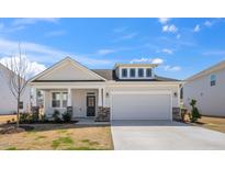 Charming home featuring stone accents, a covered porch, and a two-car garage at 217 Mallard Loop Dr, Clayton, NC 27527