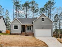 Charming new construction home with gray siding, a front porch, and an attached garage at 220 Shawnee Dr, Louisburg, NC 27549