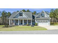 Charming home featuring a manicured lawn, stone accents, and a welcoming front porch with classic architectural details at 236 Star Valley Dr, Angier, NC 27501