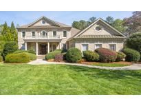 Elegant brick home featuring a manicured lawn, lush landscaping, and a covered front porch with stately columns at 2550 Bittersweet Dr, Durham, NC 27705