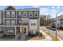 Gray townhome with stone accents, manicured landscaping, a private entrance, and visible street parking at 5200 Invention Way, Raleigh, NC 27616