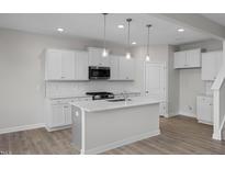 Bright kitchen with stainless steel appliances, white cabinetry, and a kitchen island at 104 Fairwinds Dr, Lillington, NC 27546