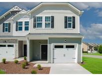 Charming two-story home with a one-car garage, landscaped front yard and black front door at 154 Rolesville Ridge Dr, Rolesville, NC 27571