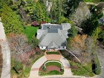 Stunning aerial view of home with manicured lawn and circular driveway with surrounding mature trees at 1925 Banbury Rd, Raleigh, NC 27608