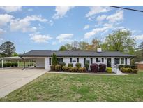 Charming one-story home with a black roof, white painted brick and a well manicured green front yard at 5121 Leesville Rd, Durham, NC 27703