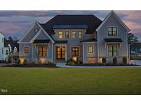 Stunning two-story home with craftsman style architecture and a manicured front lawn at twilight at 8005 Woodcross Way, Wake Forest, NC 27587