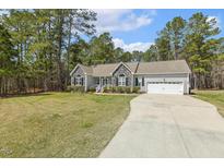 Charming home with stone accents, gray siding, a manicured lawn, and an attached two car garage at 808 Cross Link Dr, Angier, NC 27501