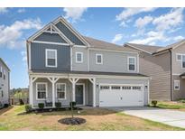 Charming two-story home featuring a covered front porch, attached two-car garage, and manicured landscaping at 1040 Lippincott Rd, Durham, NC 27703