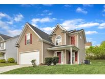 Charming two-story home with a well-manicured lawn, attached garage, and red accents on the shutters and front door at 1320 Rushing Creek Pkwy, Raleigh, NC 27610