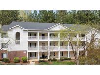 Three-story condo building with white siding, black shutters and balconies surrounded by lush trees at 2800 Trailwood Pines Ln # 301, Raleigh, NC 27603