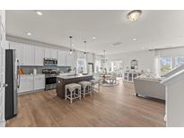 Open-concept kitchen features a center island, pendant lighting, and stainless steel appliances, blending into the dining and living spaces at 6529 Winter Spring Dr, Wake Forest, NC 27587