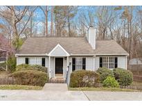 Charming single story home with light gray siding, black shutters, mature landscaping and a welcoming front entrance at 815 Riverbark Ln, Durham, NC 27703