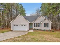 Charming single-Gathering home with attached garage and well-manicured lawn and tall trees at 100 Hillside Village Dr, Louisburg, NC 27549