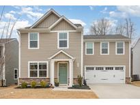 Charming two-story home featuring a two-car garage, green front door, and landscaped front yard at 329 Golden Plum Ln, Zebulon, NC 27597