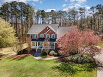 Charming brick home with blue shutters, lush lawn, and mature trees showcasing curb appeal at 3601 Tartancroft Pl, Fuquay Varina, NC 27526
