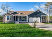 Charming home featuring a stone facade, covered porch, well-manicured lawn, and attached two-car garage at 390 Lake Magnolia Way, Smithfield, NC 27577