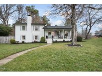 Charming two-story home featuring a brick chimney, a welcoming porch, and well-manicured landscaping at 4900 Skidmore St, Raleigh, NC 27609
