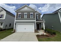 Charming two-story home featuring gray siding, brown shutters, a two-car garage, and a well-manicured front lawn at 76 Commons Cir, Clayton, NC 27520