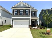 Charming two-story home with a two-car garage, well-maintained landscaping, and a welcoming front porch at 76 Commons Cir, Clayton, NC 27520