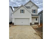 View of a two-story home with a two-car garage, stone accents, and light siding at 84 Commons Cir # 225, Clayton, NC 27520