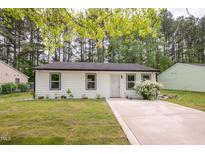 Charming home with white siding, black trim, a landscaped front yard, and a concrete driveway at 1204 Pecan Pl, Durham, NC 27704