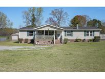 Charming single-story home featuring a cozy porch and well-maintained front yard and a detached shed at 122 Blueberry Dr, Selma, NC 27576