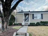 Charming tan home features a black front door, tidy landscaping, and classic curb appeal at 2706 Mcneil St St, Raleigh, NC 27608