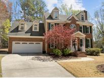 Traditional brick home with a three-car garage, dormer windows, green shutters, and a beautiful tree in the front yard at 5125 Salinas Ct, Holly Springs, NC 27540