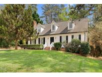 Charming home with white siding, black shutters, dormer windows, brick stairs, and a lush front lawn at 7616 Valley Run Dr, Raleigh, NC 27615