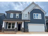 Charming two-story home featuring blue siding, white trim, and a two-car garage at 779 Old Station Pointe, Angier, NC 27501
