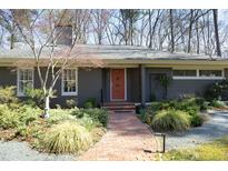 Charming front exterior featuring a brick walkway, orange door, and professionally landscaped garden at 817 Old Mill Rd, Chapel Hill, NC 27514