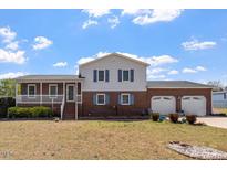 Charming two-story home with a brick facade, a cozy porch, and an attached two-car garage at 153 Glenn Oak Dr, Sanford, NC 27332
