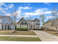 Charming two-story home featuring a well-manicured lawn, a long driveway, and mature landscaping at 215 Mystic Pine Pl, Apex, NC 27539