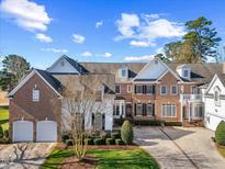 Spacious brick home with two-car garage, manicured lawn, and classic American flag display at 2308 Carriage Oaks Dr, Raleigh, NC 27614