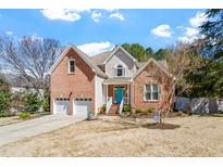 Charming brick two-story home with a two-car garage, beautiful landscaping and a bright blue front door at 4913 Carlton Crossing Dr, Durham, NC 27713
