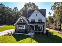 Beautiful two-story home with a stone and white facade and well-manicured lawn at 581 Magnolia Acres Ln, Fuquay Varina, NC 27526