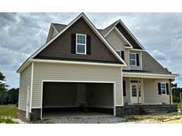 A beige two-story home exhibits a two-car attached garage and black shutters accenting the windows at 85 Prency Ln, Middlesex, NC 27557