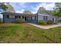 Charming single-story home with gray exterior, black shutters, and landscaped front yard with mature trees at 1 Greenfield Ct, Durham, NC 27705