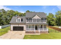 Charming two-story home featuring a welcoming front porch and attached garage at 112 Roping Horn Way, Willow Springs, NC 27592
