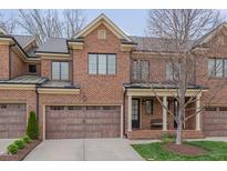 Charming brick townhome with a two-car garage, a covered entryway, and manicured landscaping at 129 Cofield Cir, Durham, NC 27707