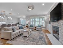 Bright living room features a brick fireplace, stylish furniture, and an open layout leading to the kitchen at 129 Cofield Cir, Durham, NC 27707