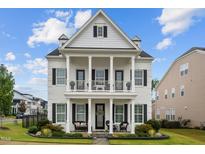 Stunning two-story home featuring a grand front porch with classic white columns and manicured landscaping at 1332 Gloriosa St, Apex, NC 27523