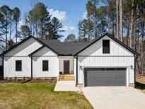Charming new construction home featuring white siding, a gray roof, and an attached two-car garage at 1429 Sagamore Dr, Louisburg, NC 27549