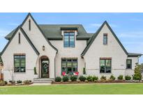 Stunning two-story white brick home with a manicured lawn and a welcoming front entrance with an arched doorway at 1801 Clifton Pines Dr, Cary, NC 27519