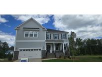 Charming two-story home showcasing stone accents, a two-car garage and manicured lawn under a partly cloudy sky at 20 Bold Dr, Youngsville, NC 27596