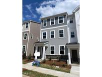 Charming three-story townhouse with gray siding, stone accents, and manicured landscaping under a sunny, partly cloudy sky at 3012 Honeymyrtle Ln, Durham, NC 27703